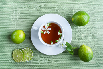 White cup with tea. Green, black, herbal, jasmine tea with lemon and ginger.Background with space for text. Tea theme.Light green, mint background