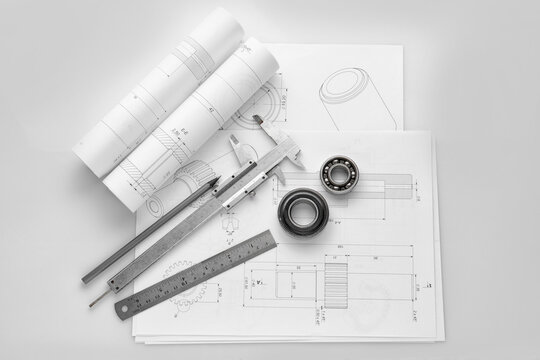 Engineering supplies and part blueprints on white background