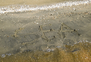 The inscription of the sea on the sand. Coastal sand and waves. Inscriptions on the shore
