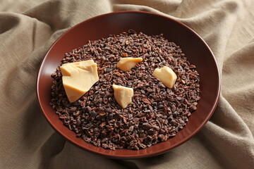 Bowl with cocoa nibs and butter on fabric background