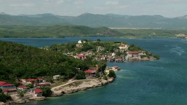 Houses on the coast of the Bay of Santiago de Cuba. Sierra Maestra mountain range on the background