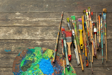 Artist's brushes in oil paint on wooden floor of studio. Creative tools