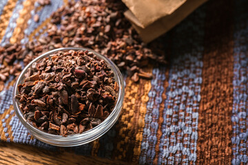 Glass bowl with cocoa nibs on table