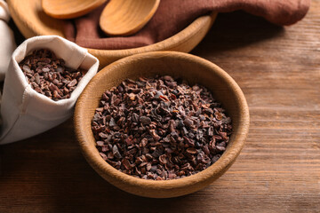 Bowl with cocoa nibs on wooden table