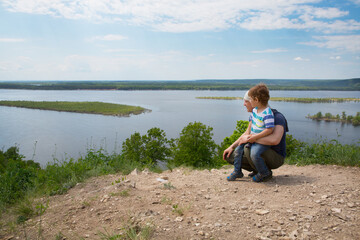 Fototapeta premium Father and child son standing on a mountaintop near River. The father shows his son the sights. Father and son travel together.