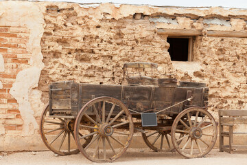 Fototapeta na wymiar Historic western horse cart dusty mud brick wall