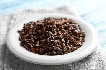 Plate with cocoa nibs on table, closeup