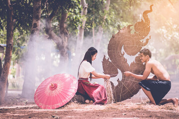 couples in traditional Ancient style costume with engraving Tool create the candle sculpture Thai...