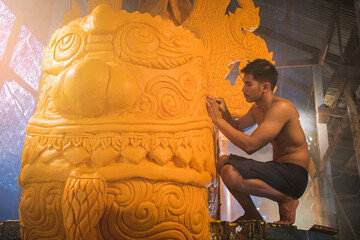 man in traditional Ancient style costume with engraving Tool create the candle sculpture for the...