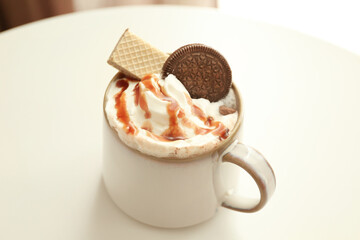 Cup with tasty cocoa drink and sweets on table