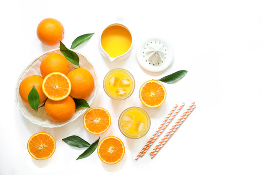 Two glasses of orange juice with ice cubes and oranges isolated on white background top view.