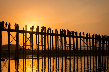 Silhouettes of people on U Bein bridge over the Taungthaman Lake at sunset, in Amarapura, Mandalay,...