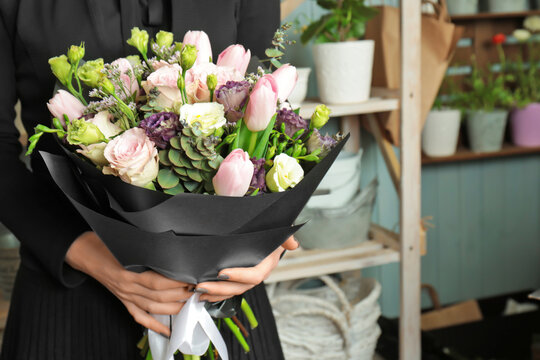 Woman holding beautiful blooming bouquet of flowers in shop