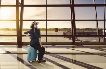 Tired asian traveler woman sitting on luggage waiting flight