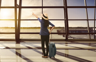 Fototapeta na wymiar Traveler asian woman with suitcase looking sunset through window