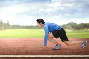 Young asian runner in start position ready to running