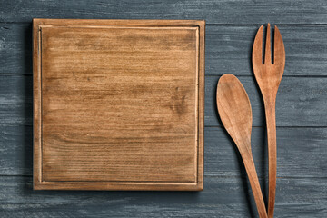 Wooden board and cooking utensils on table