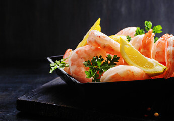 Tiger shrimps with spice and lemon on black wooden board.