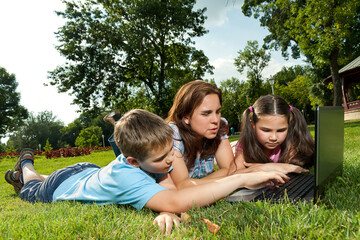 Fototapeta premium Happy Family using laptop lying on grass