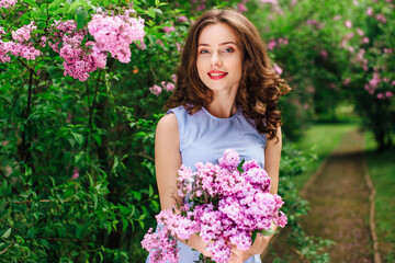 Fototapeta premium Young girl stand at park background with bouquet of flowers
