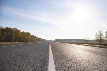 The picturesque landscape and the Sunrise over the road. Asphalt road with marking. With the blur.