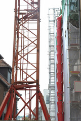 Fototapeta na wymiar Teleskop-Bauschuttrutsche am Gerüst für die Renovierung der Fassade eines Verkaufsgebäudes mit Sicherheitsnetz