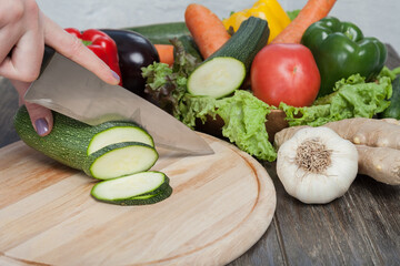 Fresh vegetables on chopping board and dark table. Zucchini cut into pieces, over a wooden table made a composition of vegetables in the form of collage. Healthy eating and healthy diet. Sliced of zuc