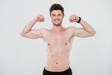 Fototapeta na wymiar Smiling shirtless sportsman showing biceps and looking at camera