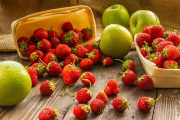 two baskets of strawberries spilled and apples 