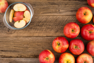 Sliced apples in a glass bowl on the old wooden table.