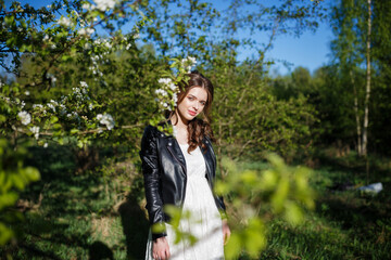 Portrait of beautiful young woman in apple trees blooming park on a sunny day. Smiling girl with apple trees flowers. Happy girl. Happiness concept.