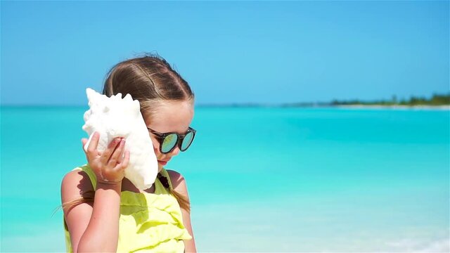 Portrait of little cute girl with a big seashell