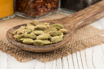 Cardamom in a wooden spoon and an old white wooden table.