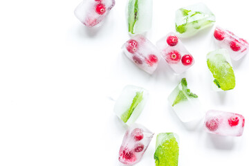 Ice cubes with berries and mint white background top view mock up