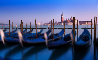 Venice sunset with motion blur effects on Gondola. Amazing blue and purple sky