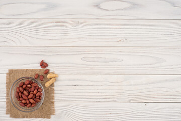 Peanuts in a glass bowl on the old wooden table.