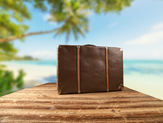 Retro luggage placed on wooden planks with tropical beach on background