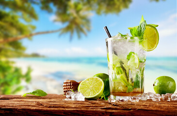 Fresh mojito drink placed on wooden planks, blur beach on background