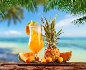 Rolgordijnen Fresh orange drink placed on wooden planks, blur beach on background © Jag_cz