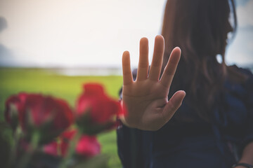 An Asian women rejecting a red rose flower from her boyfriend on Valentine's day with nature and blue sky background