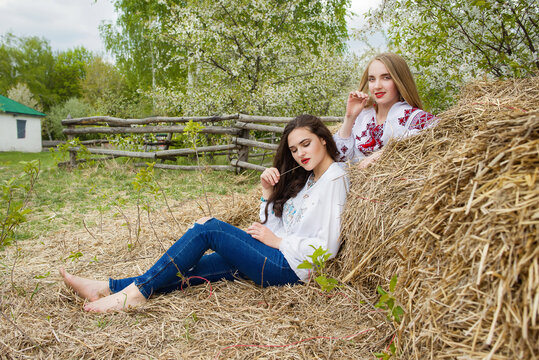 Two young beautiful  girls with long hair in Ukrainian blouses and in a wreathes in outdoor ethnic village Pirogovo in Kiev Ukraine