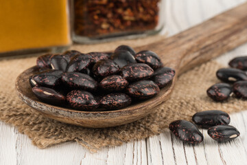 Black beans in a wooden spoon on old wooden table.