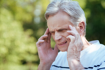 Perplexed aged man feeling awful pain outdoors