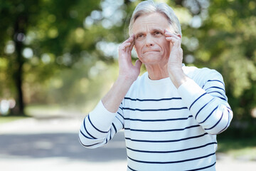 Depressed aging man feeling awful pain in head outdoors