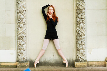 Ballet dancer. Beautiful graceful ballerine in black practice ballet plie positions near large wall, copy space