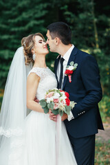 Stunning wedding couple kisses in the forest