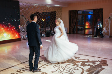 Groom and magnificent bride dance in a bright hall
