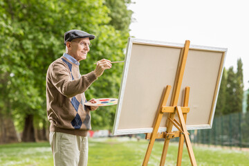 Elderly man painting on a canvas - Powered by Adobe