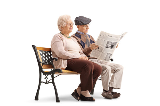 Seniors sitting on bench with one of them reading newspaper