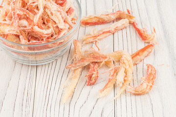 Dried squid in a glass bowl on old wooden table.